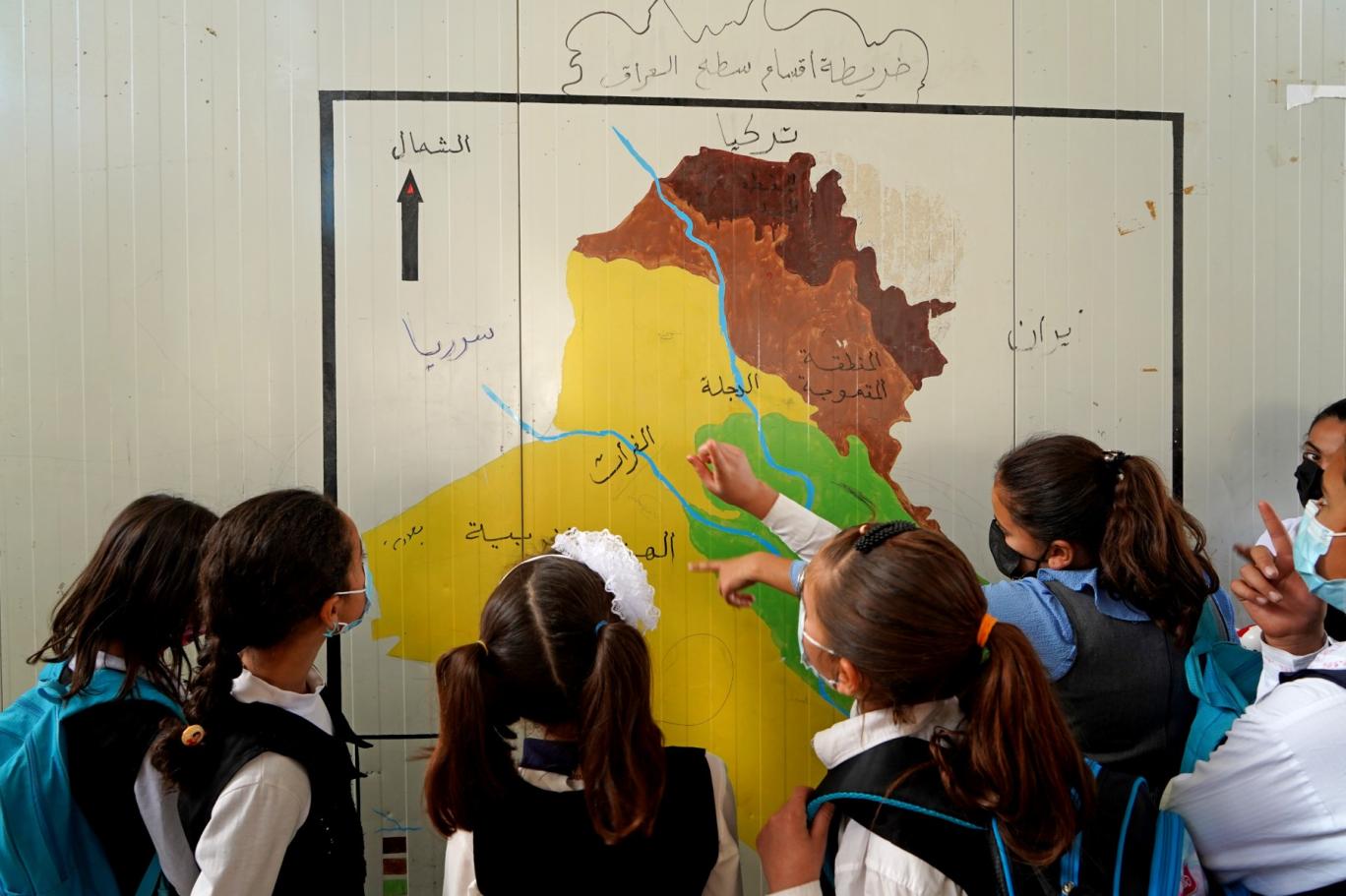 فتيات ينظرن إلى خريطة العراق في إقليم كردستان العراق المتمتع بالحكم الذاتي (أ ف ب)