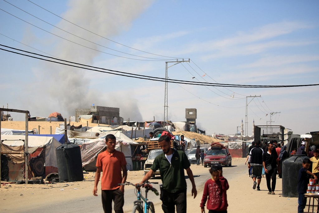 يتصاعد الدخان بعد قصف إسرائيلي بينما يسير النازحون الفلسطينيون في رفح بجنوب قطاع غزة، 31 مايو 2024 (أ ف ب).jpg