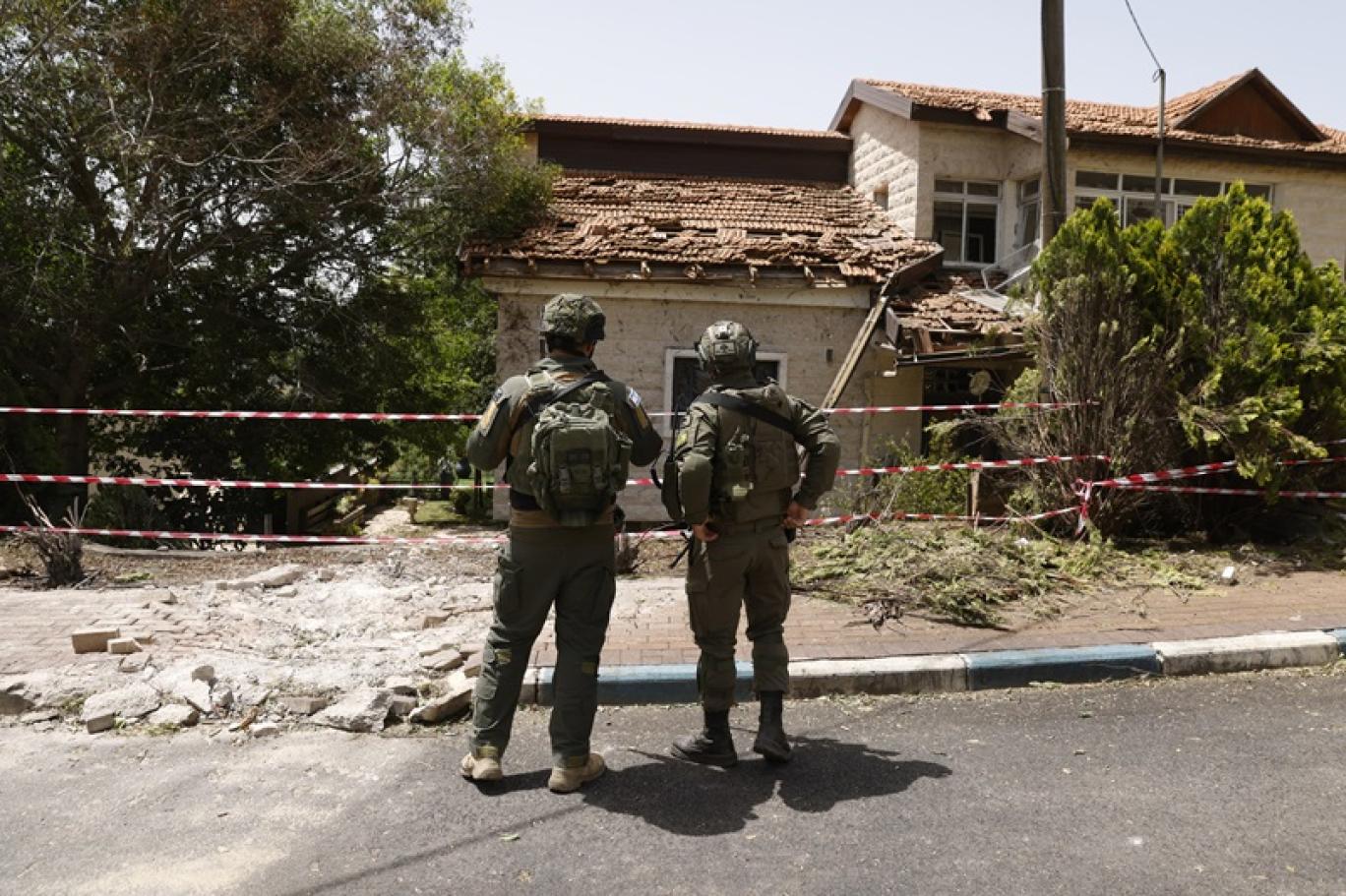 جنديان إسرائيليان يعاينان أضرار القصف في شمال إسرائيل (أ ف ب) 